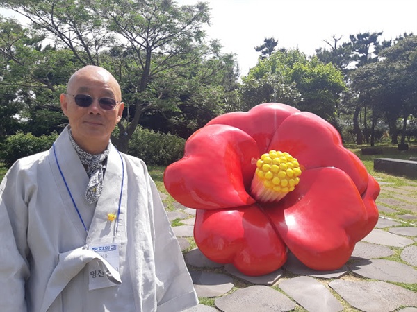 제주 4.3 평화공원에 있는 동백꽃 조형물 앞에 선 명진 스님.