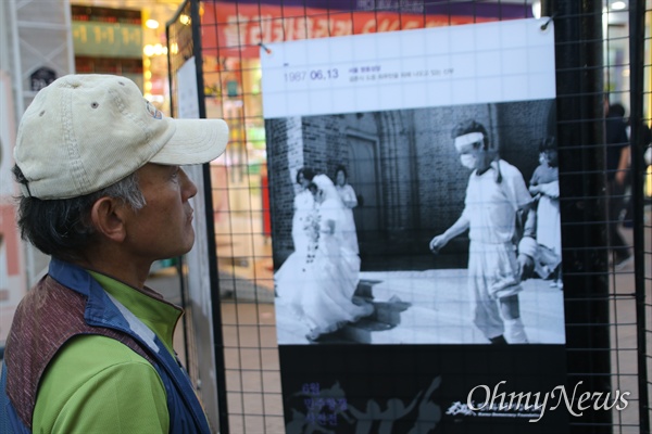 10일 오후 대구백화점 앞에서 열린 6.10항쟁 32주년 기념행사에 전시된 당시 사진들을 한 시민이 바라보고 있다.