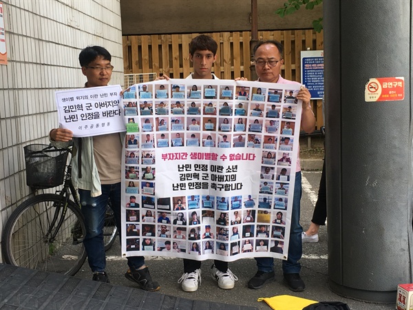 김민혁군과 난민 단체 관계자들이 '부자지간 생이별할 수 없습니다. 난민 인정 이란 소년 김민혁군 아버지의 난민 인정을 촉구합니다'라는 내용이 적힌 플래카드를 들고 있다. 