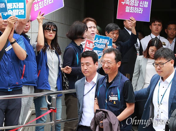 김명환 민주노총 위원장이 21일 오후 서울 양천구 남부지법에서 국회앞 불법 시위를 주도한 혐의로 구속전 피의자심문(영장실질심사)을 받고 수갑을 찬 채 나오며, 응원하는 조합원들을 향해 미소를 보내고 있다.