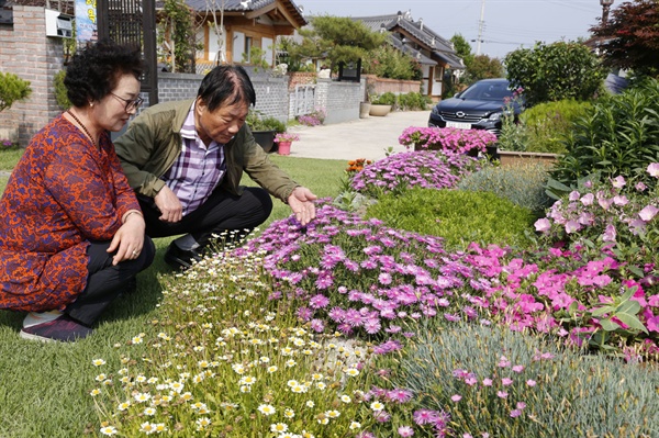 교량마을에 사는 박경숙, 김수성 씨 부부가 마당에서 자라고 있는 꽃을 살피고 있다.