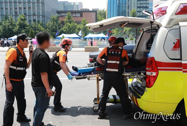 우리공화당과 충돌로 부상당한 용역직원이 119구급대에 의해 후송되는 가운데, 뒤쪽 광화문광장에는 우리공화당이 철거 5시간만에 재설치한 농성천막이 보인다.