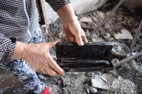 고성 산불 이재민 서(73, 여)씨가 잿더미가 된 자신의 용촌리 집터에서 불에 탄 하모니카를 꺼내 보이고 있다.