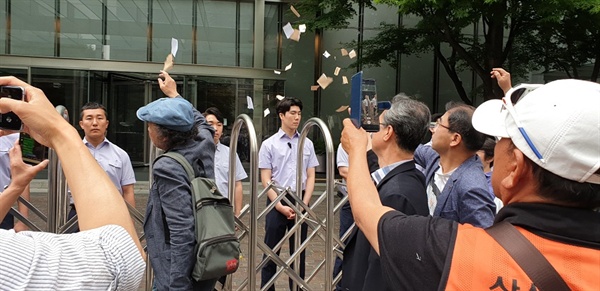 종교, 시민사회 대표들의 삼성물산의 이영호 대표이사 면담을 요구하고 있으나 거절 당하자 요구서를 찢어 울타리 안으로 날리고 있다.