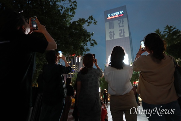 조선일보 대형 간판 아래쪽에 구호가 비추자 참가자들이 스마트폰으로 촬영하고 있다.