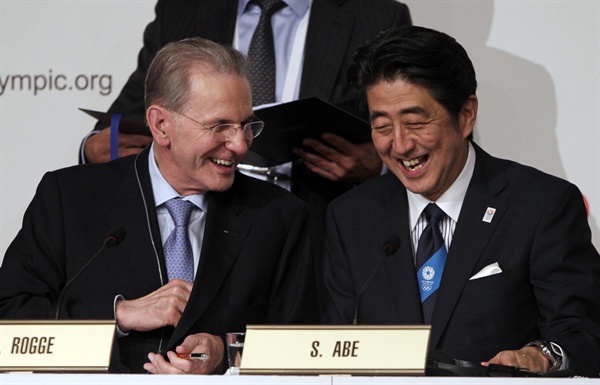 2013년 9월 7일, 아르헨티나 부에노스아이레스에서 열린 국제올림픽위원회(IOC) 제125차 총회에서 일본 도쿄가 2020년 제32회 하계올림픽 개최도시로 선정된 후 아베 신조 일본 총리(오른쪽)와 자크 로게 IOC 위원장이 개최지 선정 관련 문건에 서명한 뒤 활짝 웃고 있다. 