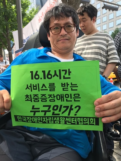 6일 오후 2시경 사회보장위원회 앞 '종합조사 모의평가 일방적 약속 파기 보건복지부 규탄 기자회견'에서 기자회견 참석자가 종이 피켓을 들어보이고 있다. 이날 기자회견을 주최한 한자협은 지난 6월 14일 장애등급제 대신 도입되는 종합조사표 문제점을 시정하고 모의평가를 공동으로 진행할 것을 요구하며 사회보장위원회를 점거했다. 