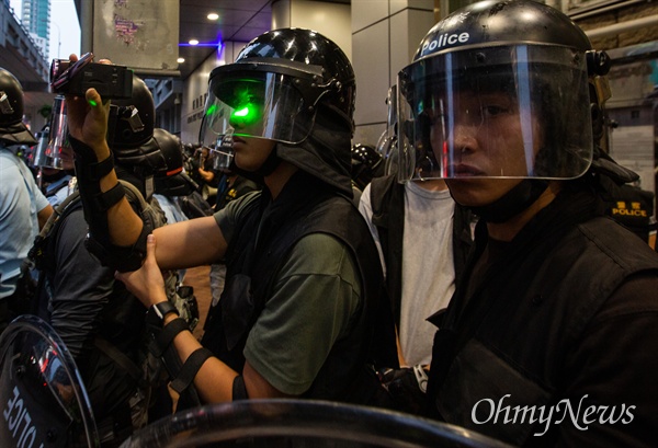 17일 오후 홍콩 몽콕 경찰서 앞에서 보호장구를 착용한 경찰이 송환법 반대 시위자들과 대치하던 중 채증을 하던 경찰의 얼굴 위로 레이저포인터의 불빛이 들어오고 있다. 