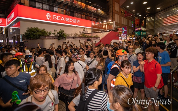 17일 오후 홍콩 몽콕 경찰서 주변에서 경찰이 송환법 반대 시위 참가자를 쫓아가자 지켜보던 시민들이 경찰을 규탄하는 구호를 외치며 스마트폰으로 촬영하고 있다. 