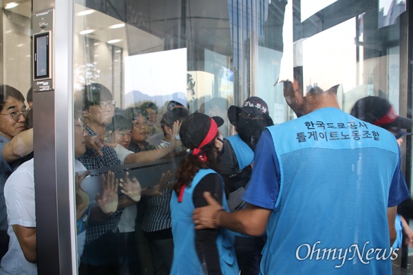한국도로공사 본사 1층에서 수납원 노동자들이 출입문을 밀고 들어오려고 하자 본사 직원들이 문을 막아 대치하고 있다.