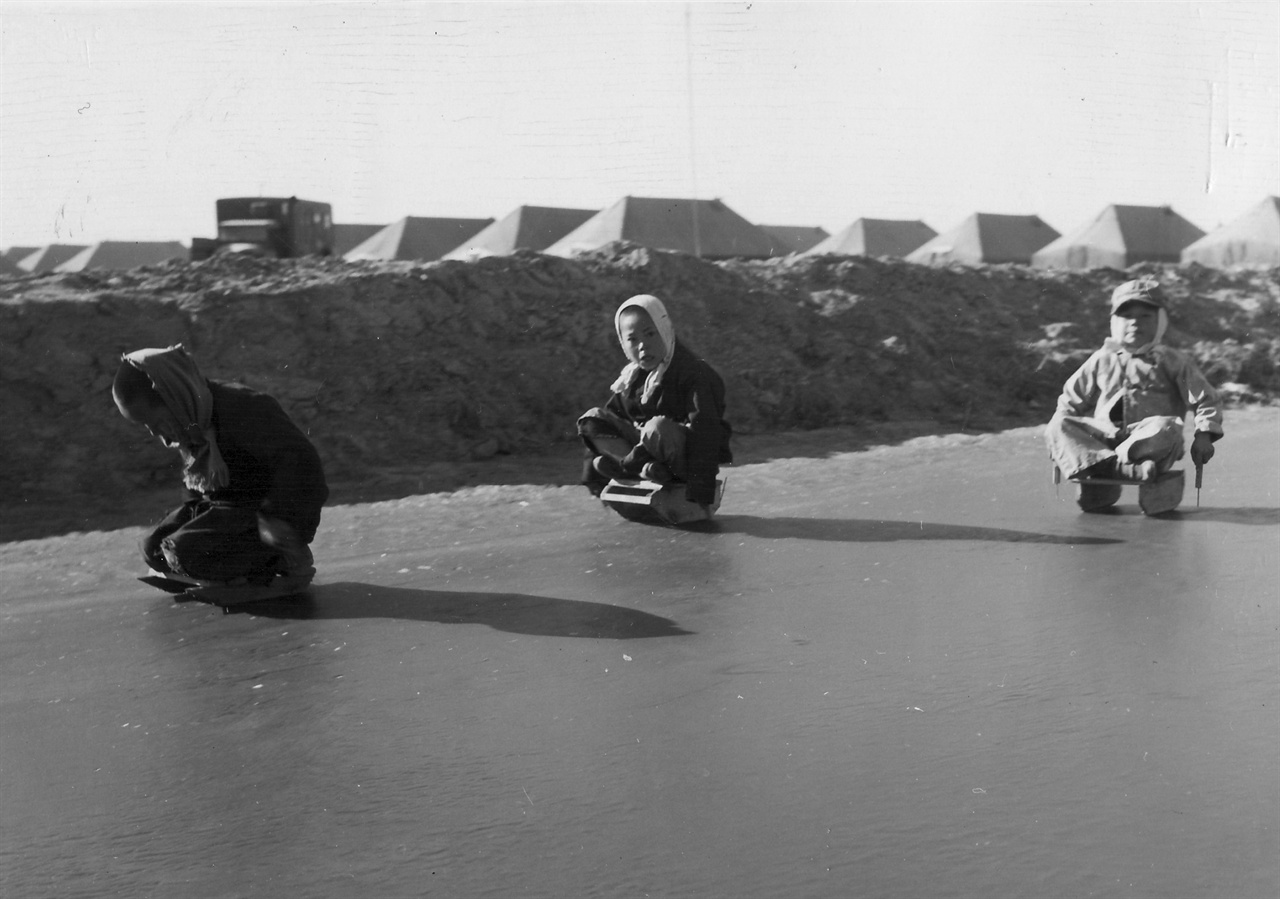 미 해병대부대 옆 빙판에서 한국어린이들이 신나게 썰매를 타고 있다(1951. 1. 28.). 