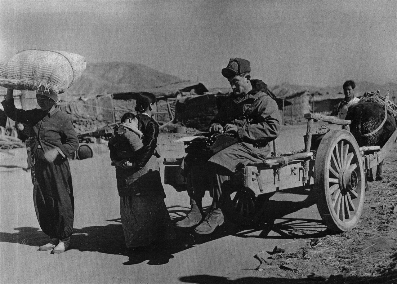 한 유엔군 측 종군기자가 소달구지 위에서 피란민 여인과 면담하면서 기사를 타이핑하고 있다(1951. 2. 6.). 