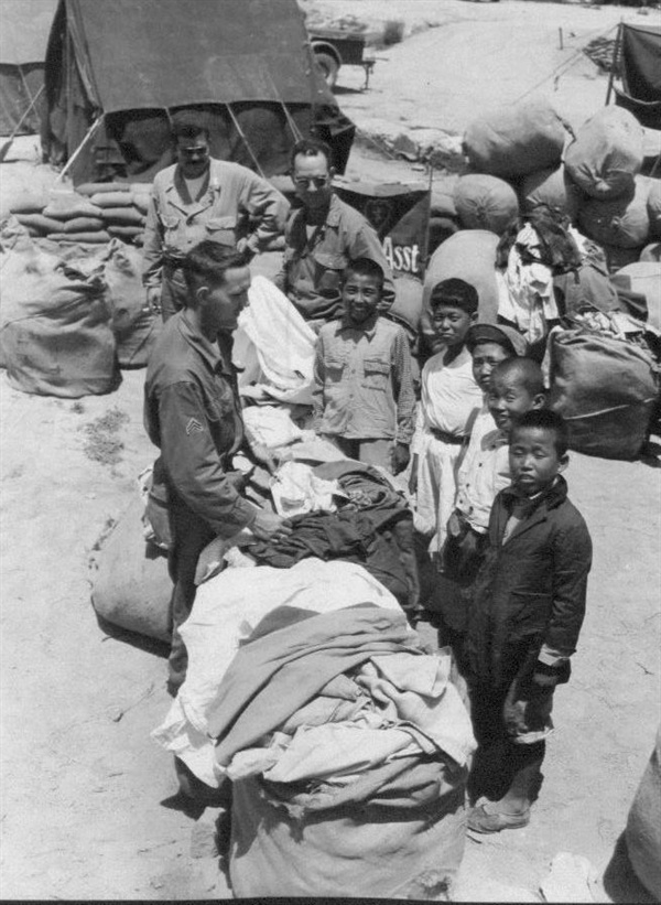 미군들이 한국인에게 구제품을 나눠주고 있다(1951. 7. 3.).