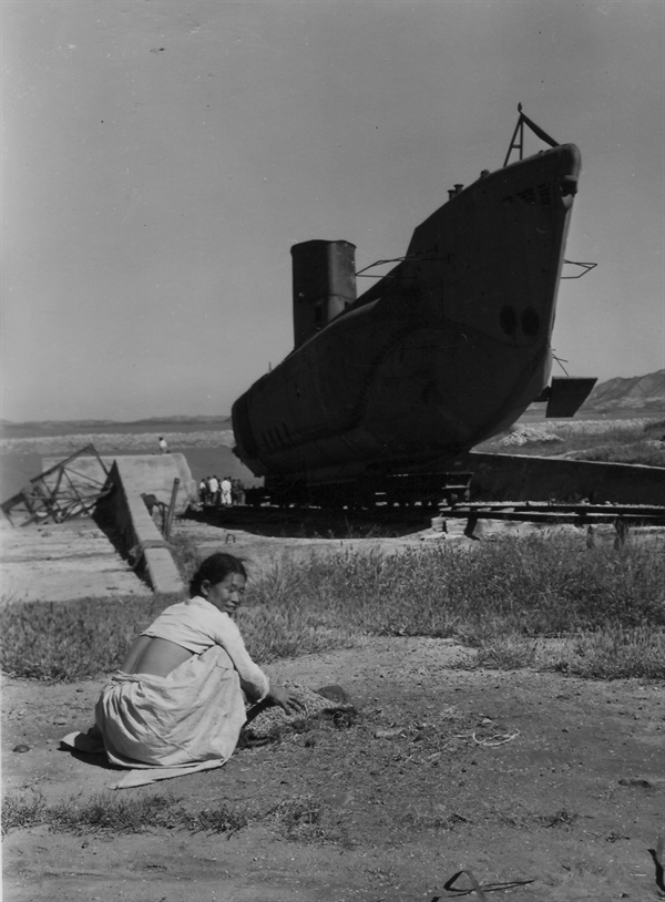 인천, 일본군이 버리고 간 낡은 잠수함이 있는 부둣가에서 땅에 떨어진 곡식을 줍는 아낙네(1952.10. 2.).  
