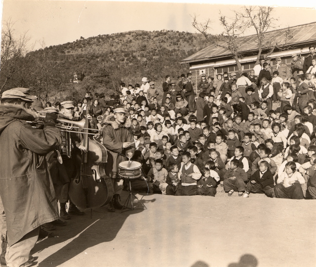 김포 반도의 한 학교 학생들이 크리스마스이브에 미 해병 제1사단 군악대의 연주곡을 듣고 있다(1952. 12. 24.).