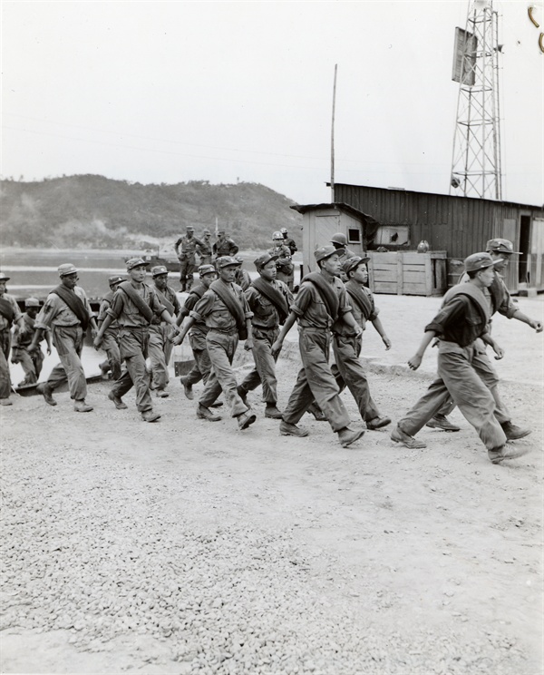북송을 원하는 공산군 포로들이 판문점으로 가는 열차에 타기 위해 행진하는 장면(1953. 8. 5.). -James H. Eveland 하사 촬영.
