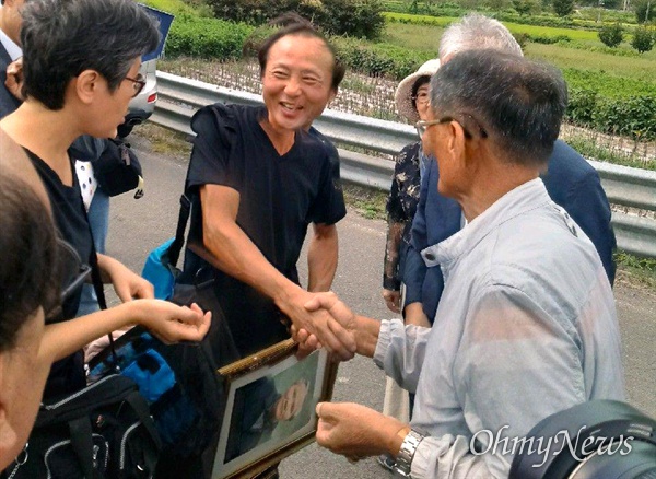 한일시민교류단 회원들이 의령 출신인 고 서정우 선생의 친족묘지를 찾아 참배했다. 사진은 서정우 선생의 아들이 아버지의 사진을 들고 친척들을 만나 인사하는 모습.