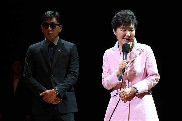2014년 8월 27일 당시 박근혜 대통령이 ‘문화가 있는 날' 행사의 일환으로 서울 상명아트센터에서 '하루(One Day)'를 관람하기에 앞서 무대에 올라 인사말을 하고 있다. 왼쪽으로 차은택 공연 총연출자가 보인다.