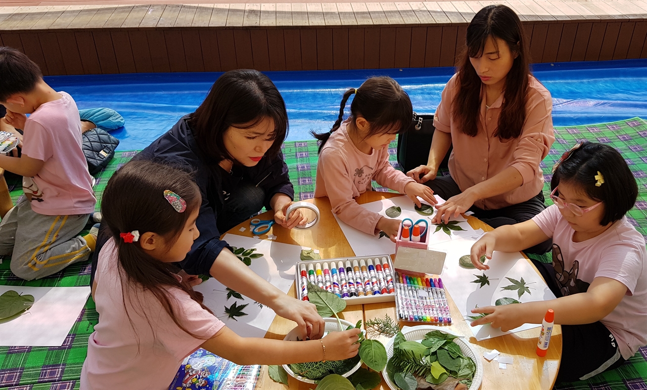 천안성정유치원 옥상 정원에서 유아와 학부모가 함께 나뭇잎 콜라주 체험 수업을 하고 있다.