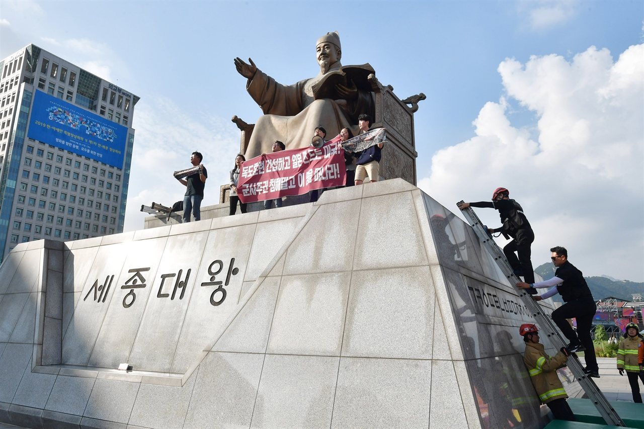  한국대학생진보연합 소속 대학생 6명이 4일 오후 서울 세종로 광화문광장내 세종대왕 동상에 올라가 ‘한일 군사정보보호협정(GSOMIA·지소미아)’ 파기를 방해하는 미국을 규탄하는 기습시위를 벌이고 있는 가운데 경찰이 학생들을 해산 시키기 위해 사다리를 이용해 동상위로 올라가고 있다.2019.10.04
