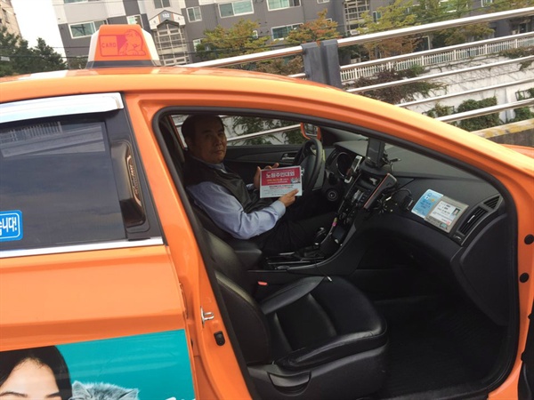 주민대회 홍보 전단을 들고 웃는 택시노조 조합원.