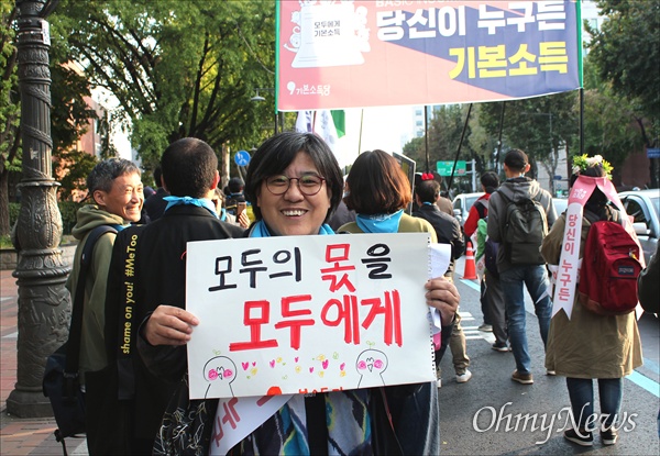 26일 전 세계 10개국 26개 도시에서 기본소득 지지자들이 기본소득을 알리고 기본소득 실현을 요구하는 “국제기본소득행진(Basic Income March)”을 동시에 진행했다. 서울에서도 대학로에서 보신각까지 150여 명의 지지자들이 행진을 벌이며 시민들에게 기본소득의 필요성을 설명했다. 행진에 참여한 한승인(55)씨가 "모두의 몫을, 모두에게"라고 적힌 손 피켓을 들고 있다. 
 