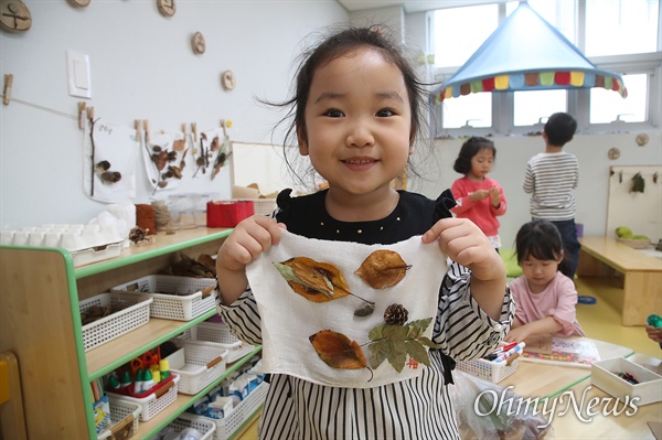 25일 오후 서울 영등포구 다온어린이집에서 한 아이가 생태친화 수업으로 가져온 나뭇잎과 솔방울로 꾸민 작품을 자랑하고 있다.