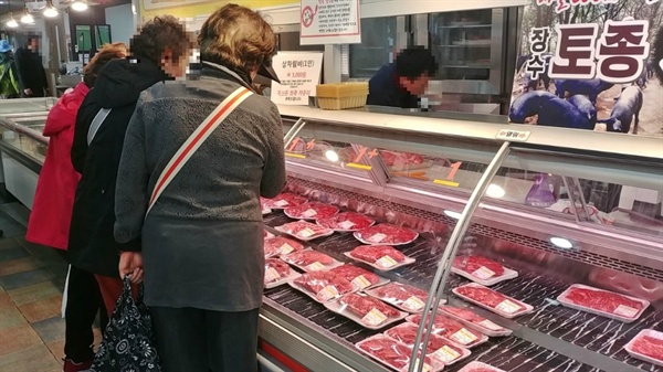 장수한우명품관 매장에서 고객들이 장수한우 고기를 구입하기 위해 살펴보고 있다.