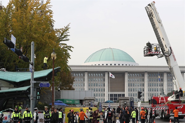 6일 여의도 국회 정문 앞 지하철역 출입구 지붕 위에 '형제복지원 사건 진상규명하라'라고 적힌 점퍼를 입은 한 남성이 시위를 벌이고 있다. 