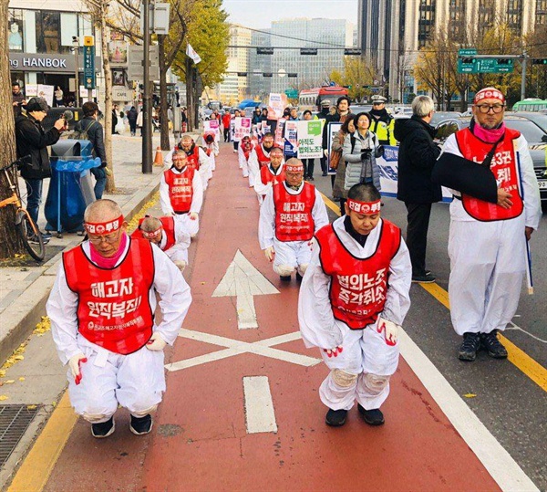 지난 11월 18일, 전교조 법외노조 해직교사들이 삭발 후 청와대를 향해 오체투지를 하고 있다. 앞줄 왼쪽으로부터 손호만 전교조 해고자 원복투 위원장, 박세영 해직교사, 조창익 전 전교조 위원장(10월 29일, 서울고용노동청 농성 중 경찰의 폭력적인 연행으로 팔 부상)