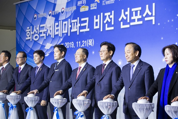 21일 오후 화성시 송산그린시티 내 동측 부지에서 열린 '화성 국제테마파크' 비전 선포식에서 이재명 경기도지사와 홍남기 경제부총리 및 기획재정부 장관, 정용진 신세계그룹 부회장, 서철모 화성시장, 이학수 한국수자원공사 사장, 서청원 국회의원, 송옥주 국회의원, 김성재 문화체육관광부 차관보, 박광석 환경부 기획조정실장 등 주요 참석자들이 성공기원 터치버튼을 하며 기념촬영을 하고 있다. 