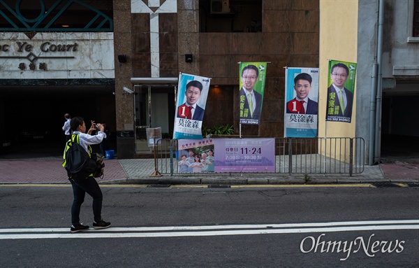 구의원 선거가 치러지는 24일 오전 홍콩 미드레벨 레이몬드 대학에 차려진 투표소 인근에서 한 기자가 후보자 포스터를 촬영하고 있다. 