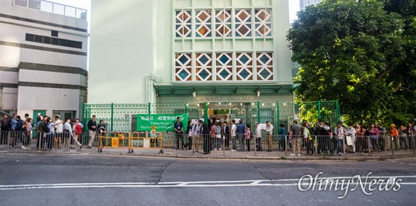 구의원 선거가 치러지는 24일 오전 홍콩 미드레벨 레이몬드 대학에 차려진 투표소에 시민들이 투표를 하기 위해 길게 줄을 서 있다.