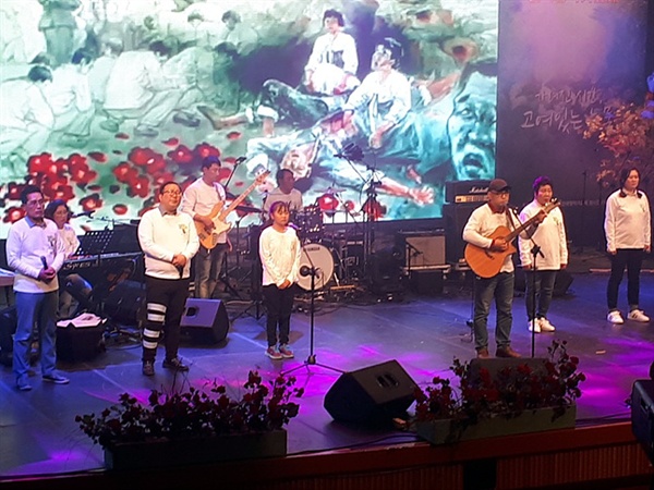  여수에서 온 상록수 밴드 멤버들이 '꽃물이 든다'라는 주제의 노래를 하고 있다. 당시 희생된 시신들을 동백꽃으로 형상화한 노래다.  