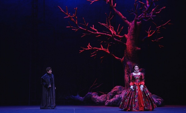  1막 2장 스투아르다(소프라노 이다미)와 로베르토(테너 이재식). 붉고 황량한 나무는 스투아르다의 혈통을 상징한다. 