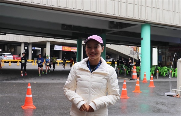 안정은씨 뒤로 2019 손기정 평화 마라톤 대회 참가자들이 달리고 있다.