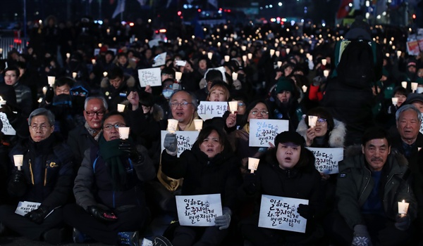 '김용균 1주기 추모위원회' 주최로 7일 오후 서울 종로구 보신각 앞에서 열린 추모대회에서 고 김용균 씨의 어머니 김미숙 씨 등 참가자들이 촛불을 들어보이고 있다.