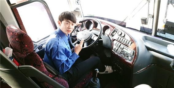 자신의 관광 버스 운전석에 앉아 포즈를 취하고 있는 김진성 씨.