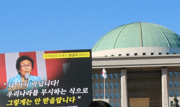 국회 앞 기자회견, 양금덕 할머니의 말이 적힌 피켓이 국회 의사당을 배경으로 보여지고 있다
