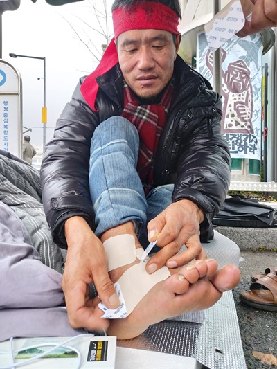 환경부 세종청사 앞에서 7일째 단식농성중인 김경배 씨가 차 사고로 다친 발목에 파스를 붙이고 있다.