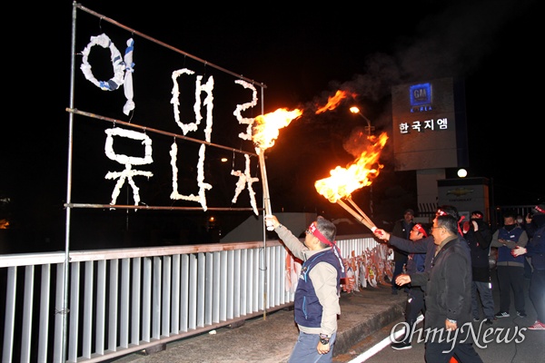 민주노총 경남본부는 18일 늦은 오후 한국지엠 창원공장 앞에서 “한국지엠 비정규직 대량해고 박살 경남노동자대회”를 열었고, "이대로 못 나가" 글자를 만들어 불을 붙이고 있다.