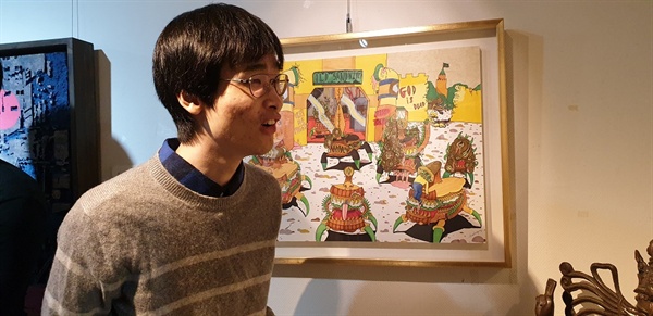 전통적인 미술 교육을 받지 않고 그만의 세게를 표현하여 '날 것'이라는 평가를 받고 있는 김치형이 자신의 작품 앞에 서 있다.