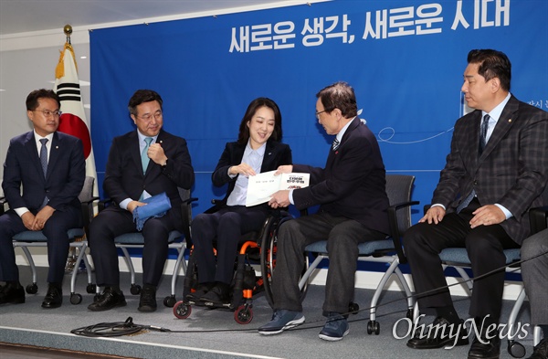 민주당 첫 영입인재 최혜영 씨 맞이한 이해찬 대표 더불어민주당 이해찬 대표가 26일 서울 영등포구 중앙당사 강당에서 민주당의 첫 영입인재 최혜영 씨에게 당 강령과 당헌, 당규가 소개된 책자를 선물하고 있다. 이날 이 대표는 휠체어에 앉은 최 씨와 눈높이를 맞추기 위해 의자에 앉은 채로 최 씨를 맞이했다.  