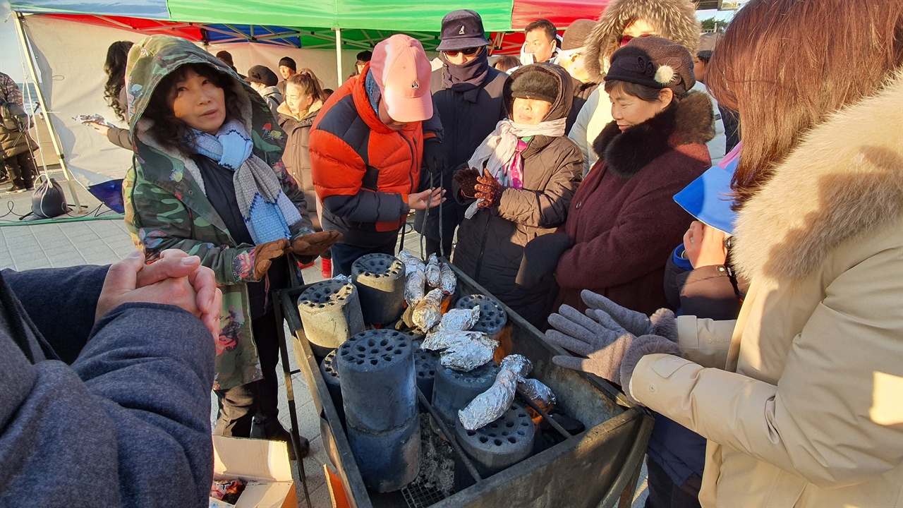 관객이 고구마 굽는 틀에 고구마를 올려놓고 굽고 있다.