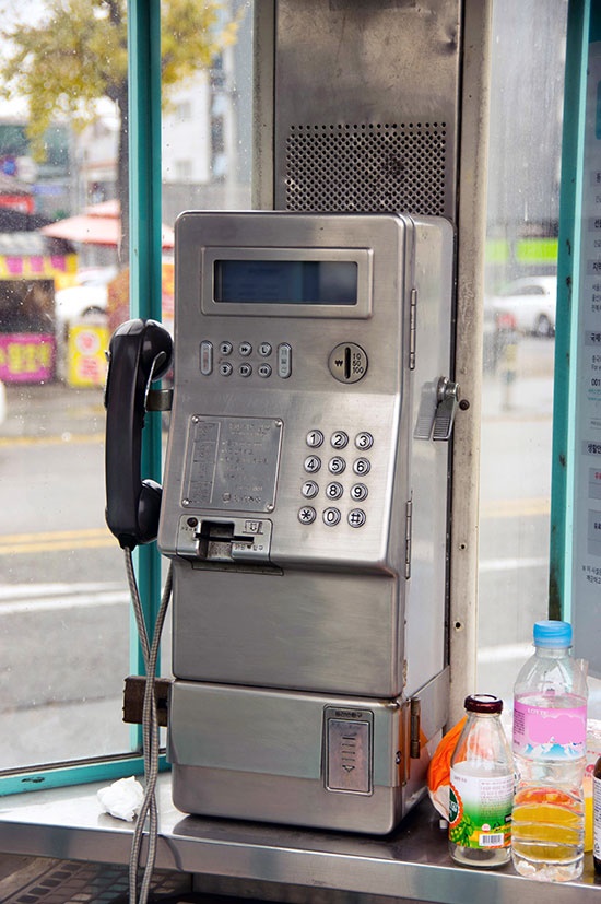  빈 물통과 음료병, 휴지 따위가 놓여 있는, 도시의 버스정류장 주변의 공중전화 부스 안 풍경은 퇴조하는 공중전화의 처지를 반영하고 있다. 