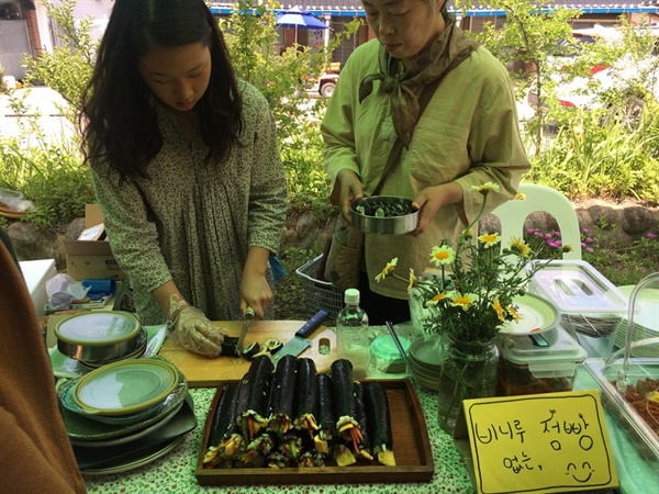 마을 초등학생이 김밥을 준비해서 ‘비니루없는점빵’ 부스에서 판매하고 있다. 주민들이 들고 온 도시락통, 판매자가 준비한 사기 접시 등에 김밥이 담긴다. 