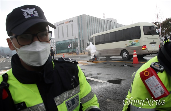 우한에서 귀국한 교민을 태운 경찰버스가 31일 오후 충북 진천 국가공무원인재개발원에 도착하자, 방역 관계자가 고압분무 세척소독기로 소독작업을 하고 있다.