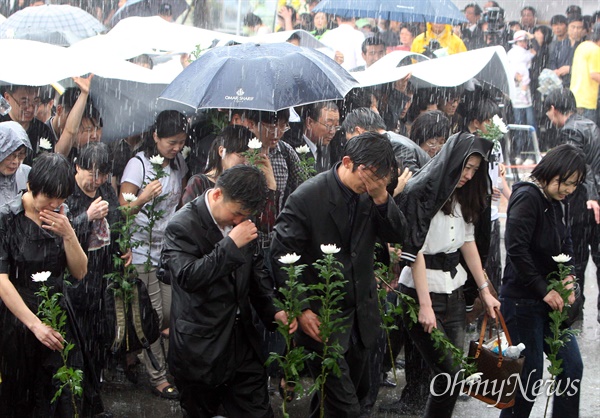 노무현 전 대통령 서거 이틀째인 24일 오후 경남 김해시 봉하마을에 마련된 노 전 대통령의 분향소에서 시민들이 폭우를 맞으며 조문하러 분향소로 들어가고 있다.