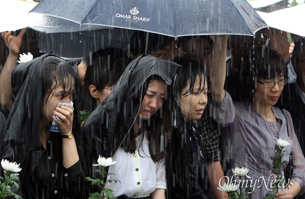 노무현 전 대통령 서거 이틀째인 24일 오후 경남 김해시 봉하마을에 마련된 노 전 대통령의 분향소에서 시민들이 폭우를 맞으며 조문하기 위해 차례를 기다리고 있다.