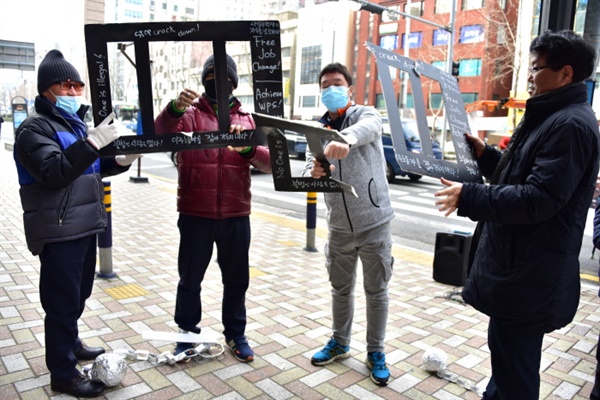 두 명의 이주노동자들이 나와 모형 창살을 부수고 발목을 휘감은 족쇄를 끊었다.